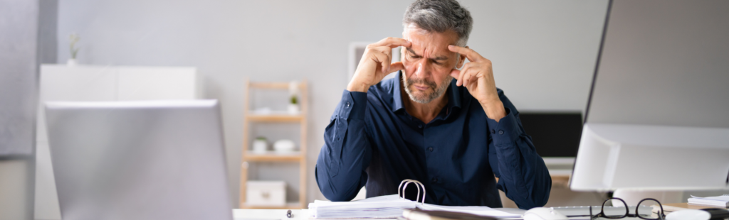 frustrated small business owner sits at desk looking at his accounting